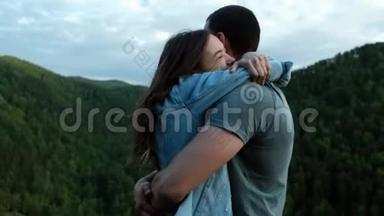一个年轻的女人高兴地拥抱她站在山顶上的男朋友。